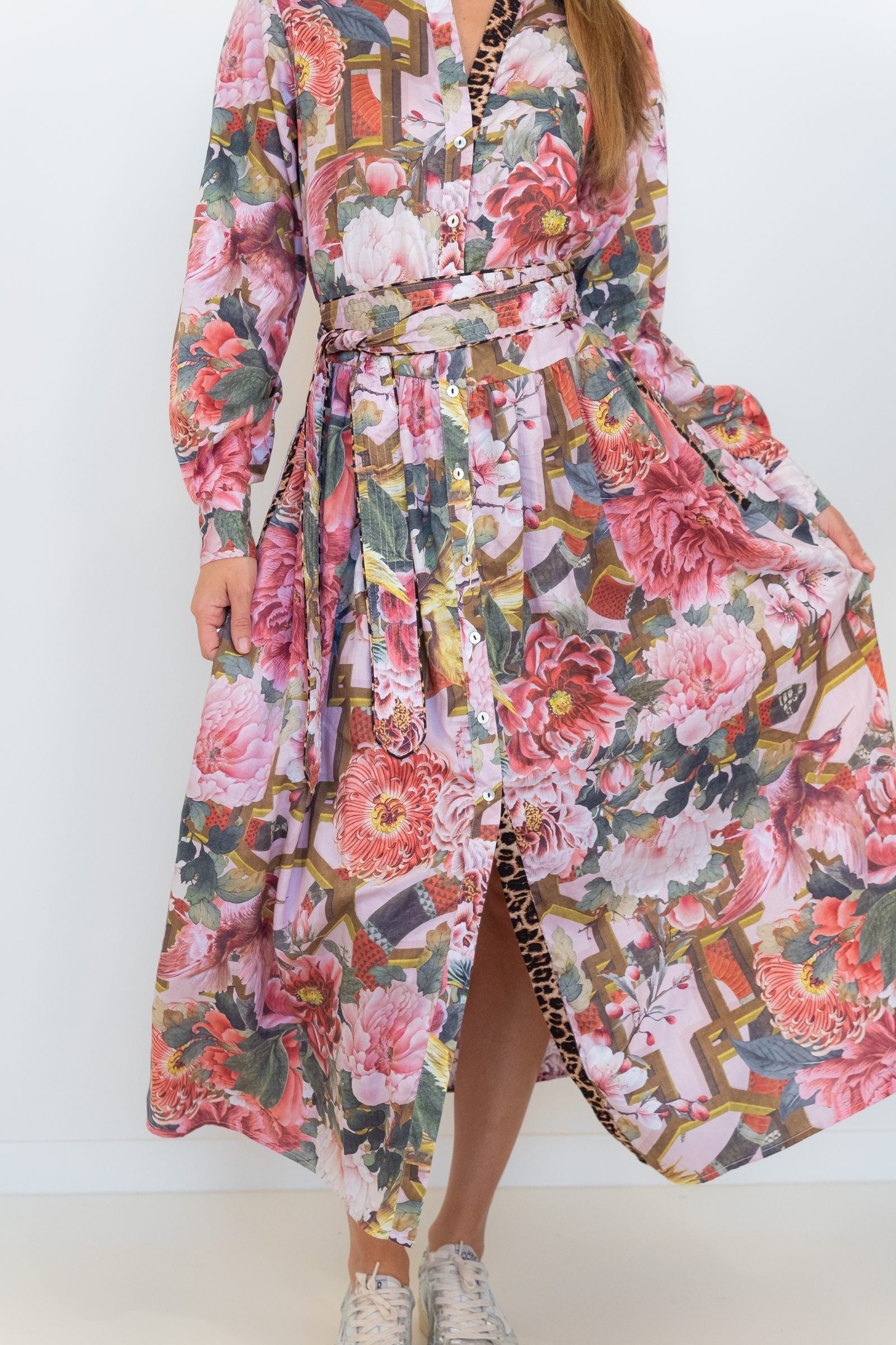 Front view of the pink floral-and-chain print drop-waist dress with the skirt slit open.
