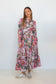 Full-length front view of a model wearing the pink floral-and-chain print drop-waist dress with long sleeves.
