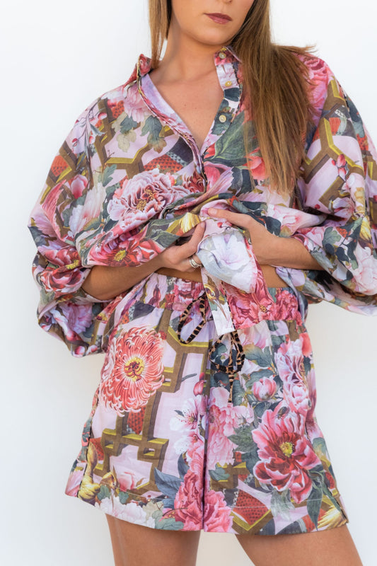 Front view of a model wearing Ophelia pink floral shorts with leopard piping and a matching floral shirt.