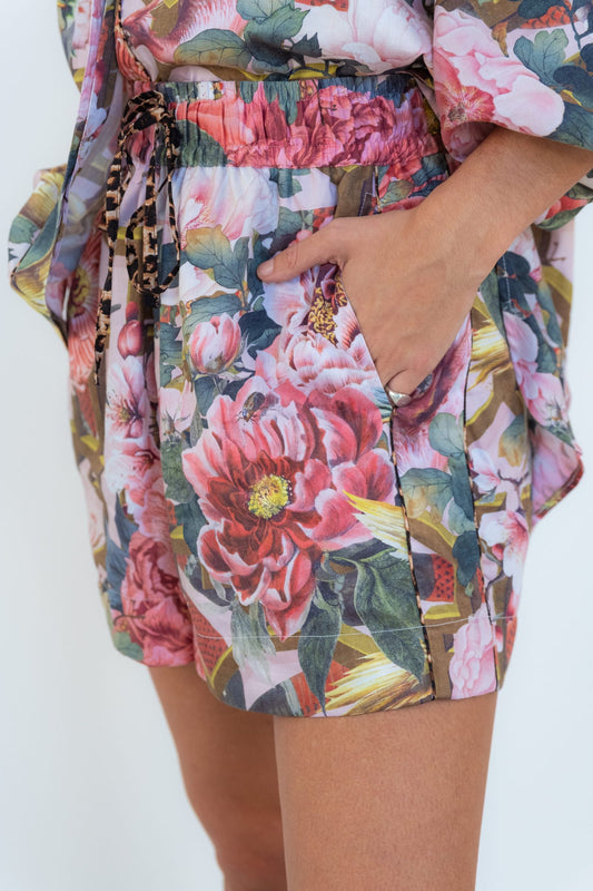 Close-up of Ophelia pink floral shorts with an elasticated waist, leopard-print drawstring, and a model’s hand in the side pocket.