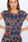 Close-up front view of the navy snakes-and-florals print on the smocked bodice.