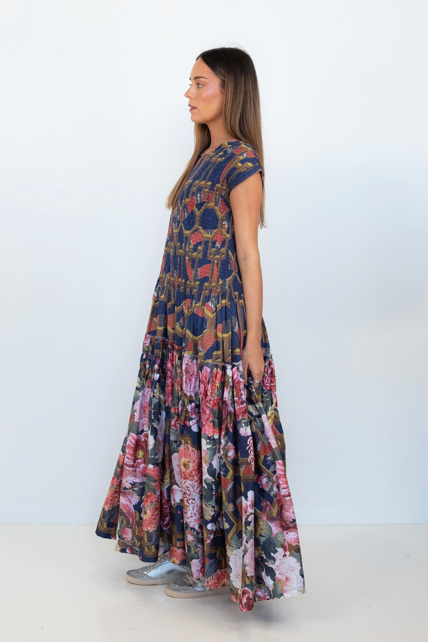 Side view of a model wearing the Ophelia snakes and florals smocked tiered maxi dress.